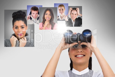 Smiling woman looking at flying portraits of business people with binocular