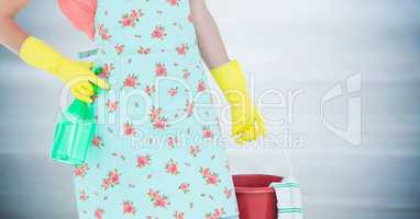 Woman lower body in apron with bucket against blurry grey wood panel