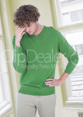 Stressed worried man in green jumper by windows