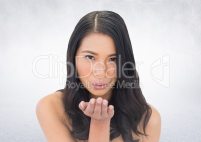 Woman blowing kiss against white wall