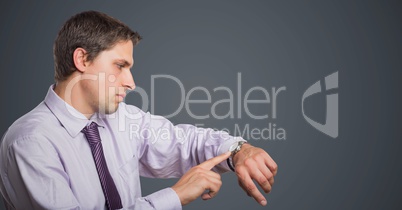 Man in lavender shirt looking at watch against grey background