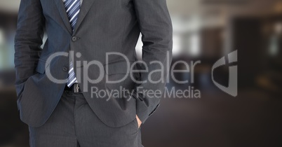 Business man mid section with hands in pockets in blurry room
