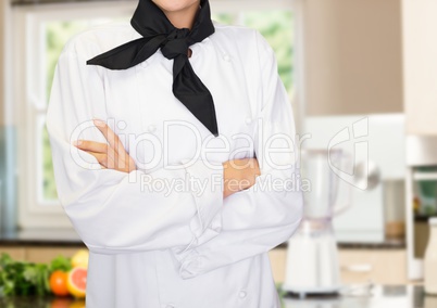 Chef arms folded against blurry kitchen