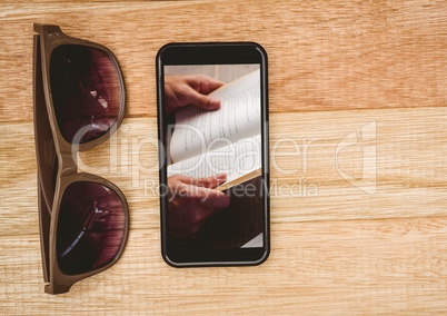 Sunglasses and phone showing open book