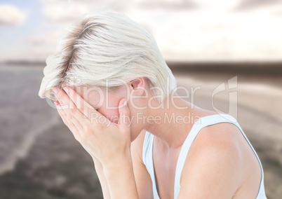 Sad woman with face in hands against sea landscape