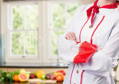 Chef arms folded against blurry kitchen with vegetables