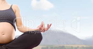 Pregnant woman Meditating by mountains