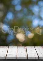 White wood table against blurry leaves