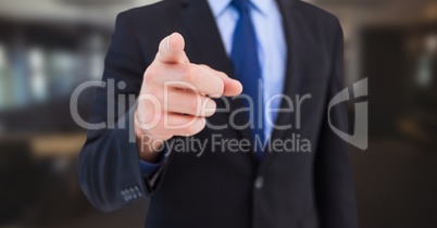 Business man mid section pointing in blurry room