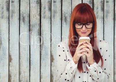 Woman looking down at coffee cup against wood panel