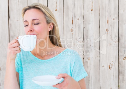 Woman drinking from white cup against white wood panel