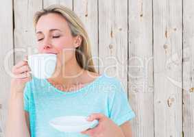 Woman drinking from white cup against white wood panel