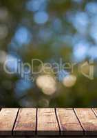 Wood table against blurry leaves