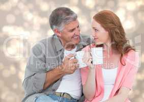 Man and woman with white mugs against cream bokeh