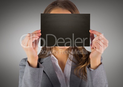 Business woman with black blank card over face against grey background