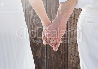 Wedding couple holding hands against wood