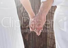 Wedding couple holding hands against wood