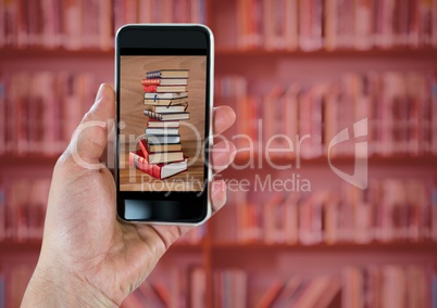 Hand with phone showing book pile against blurry bookshelf with red overlay