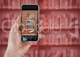 Hand with phone showing book pile against blurry bookshelf with red overlay