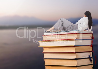 Businesswoman lying on Books stacked by sea lake
