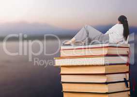 Businesswoman lying on Books stacked by sea lake