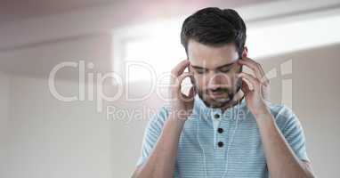 Stressed man on headphones relaxing by window light