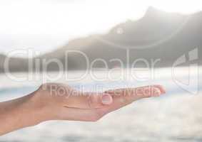 Open palm hand in front of ocean and mountains