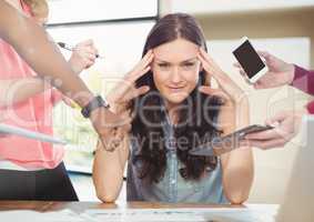 Stressed woman at desk surrounded by technology phone tablet and files