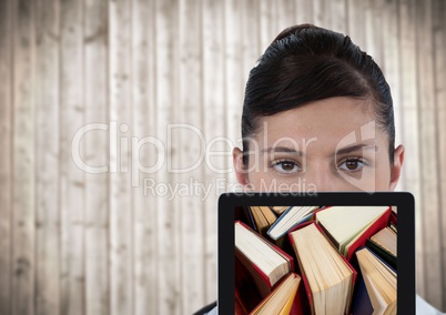 Woman with tablet showing standing books against blurry wood panel