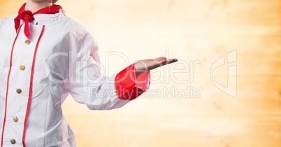 Chef with hand out at side against blurry yellow wood panel