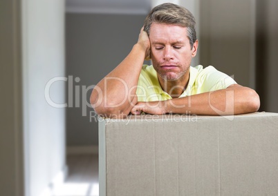 Sad man with cardboard box parcel against hall