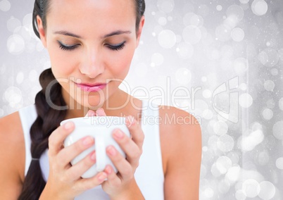Close up of woman looking down at white cup against white bokeh