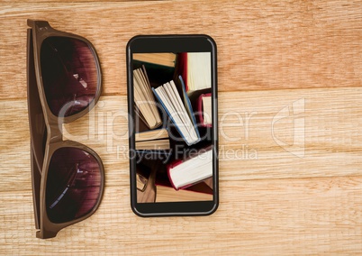 Sunglasses and phone showing standing books