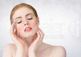 Woman with hands on face against white wall