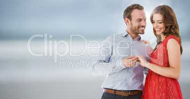Couple engaged against blurry beach