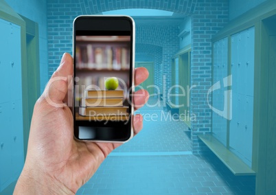 Hand with phone showing book pile with green apple against hallway with blue overlay