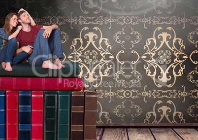 Couple sitting on Books stacked by wallpaper antique decorative