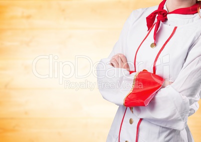 Chef arms folded against blurry yellow wood panel