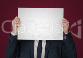 Business man with blank card over face against maroon background