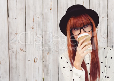 Woman in polka dot shirt with coffee cup over face against white wood panel