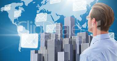 Businessman facing City with world map and email icons