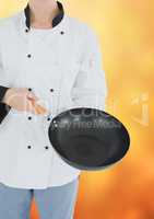 Chef with wok against blurry yellow background