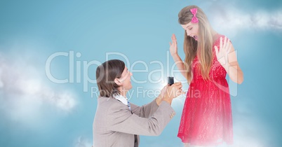 Man proposing to woman against blue background with clouds