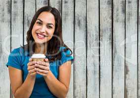 Woman in blue tshirt with coffee cup against wood panel