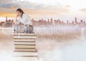 Businesswoman sitting on Books stacked by distant city