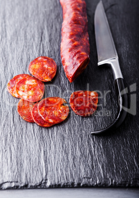 Spanish chorizo with a knife on a stone plate.