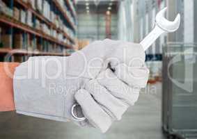 Mechanic hand with wrench against blurry warehouse