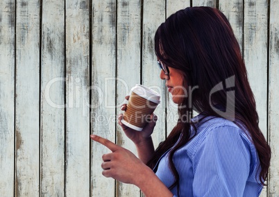 Woman drinking from coffee cup and pointing against wood panel