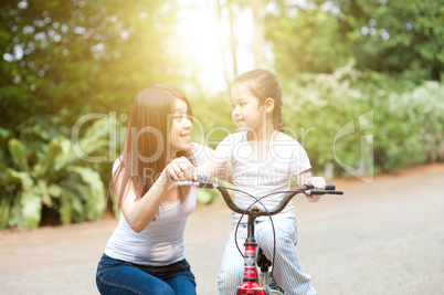 Mother and daughter riding bike outdoor.