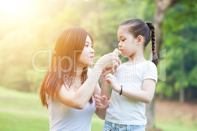 Mother and daughters eating at outdoors park.